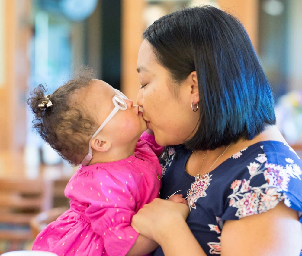 mother kissing young daughter on chin