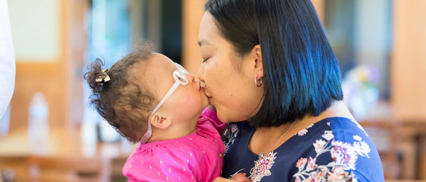 mother kissing young daughter on chin