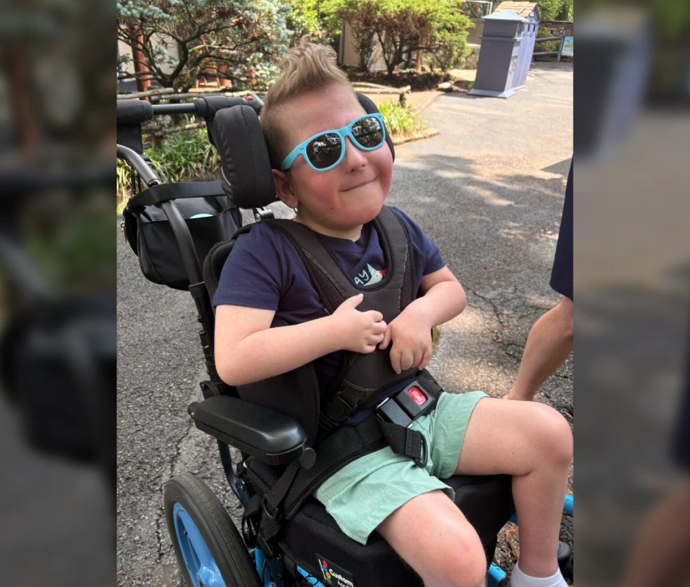 young boy in wheelchair with blue sunglasses