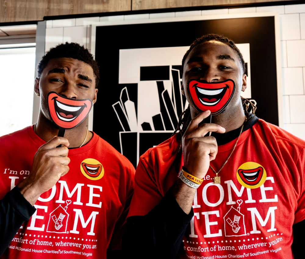 student athletes with paper smiles held up to their faces